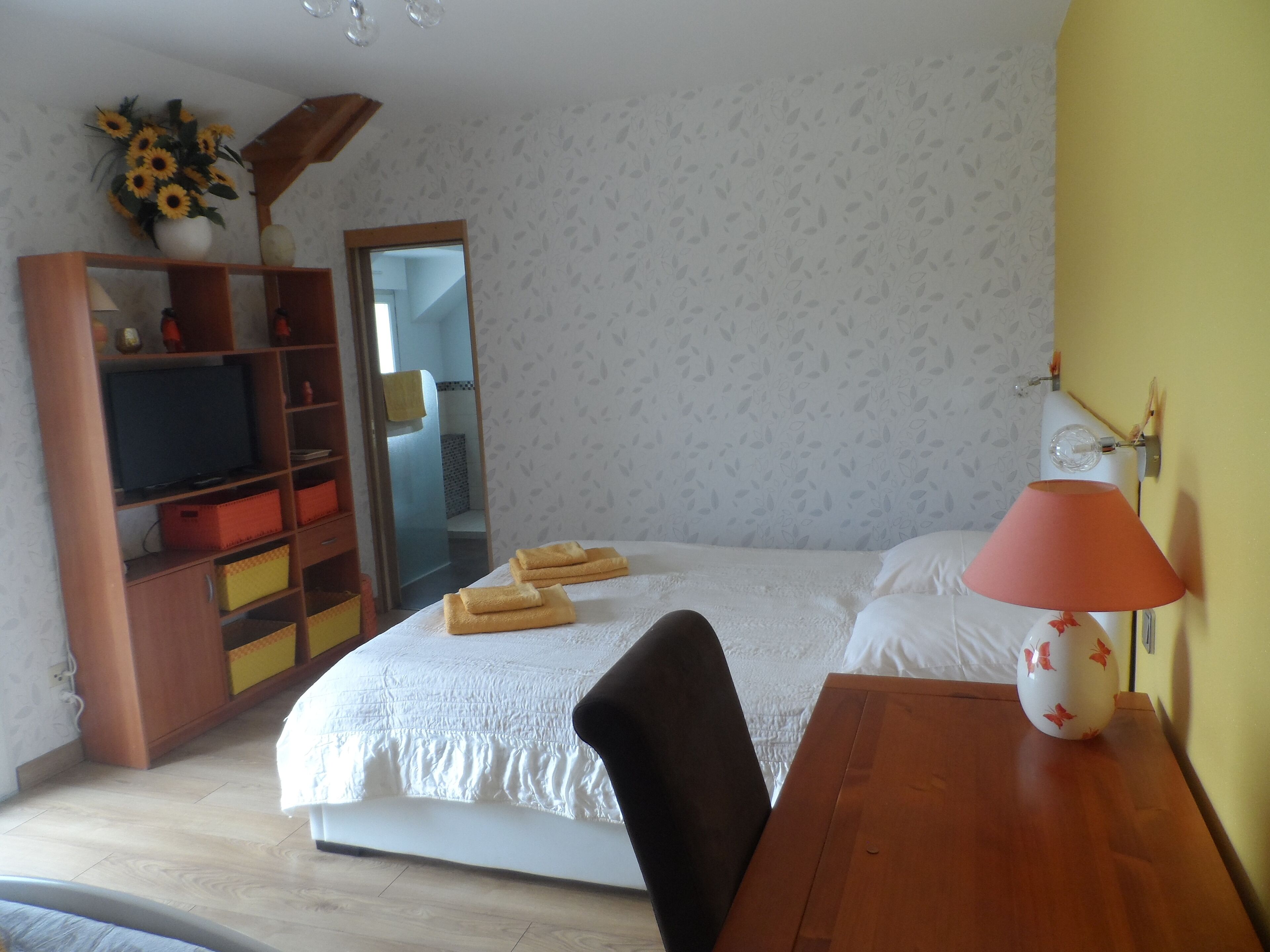 Une chambre à coucher avec un lit, un bureau en bois, une lampe, une télévision et un miroir.