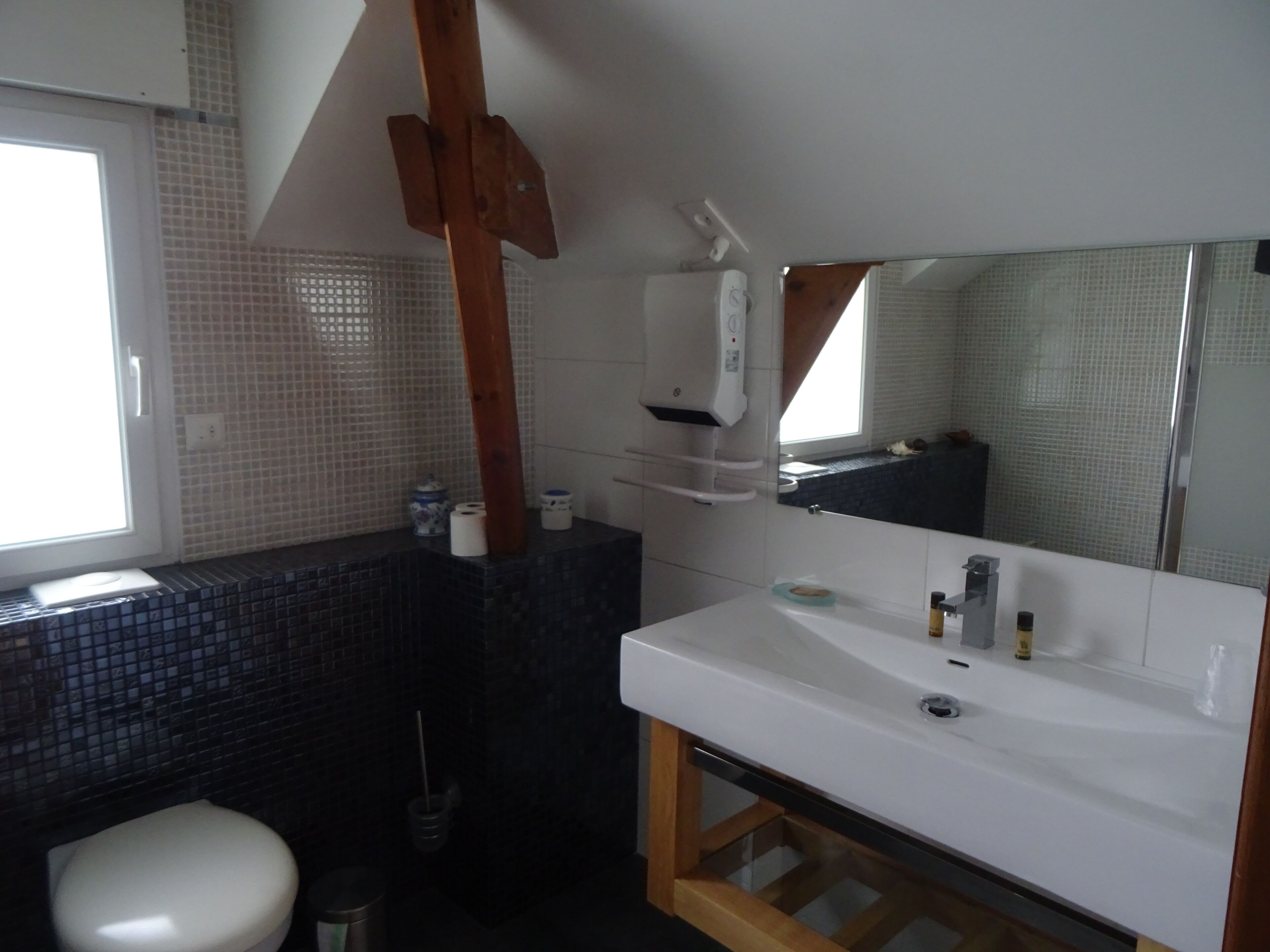 A bathroom with a white sink, a mirror, a toilet, and a window.