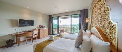 A hotel room with a large bed, a desk, a television, and a balcony with a view.