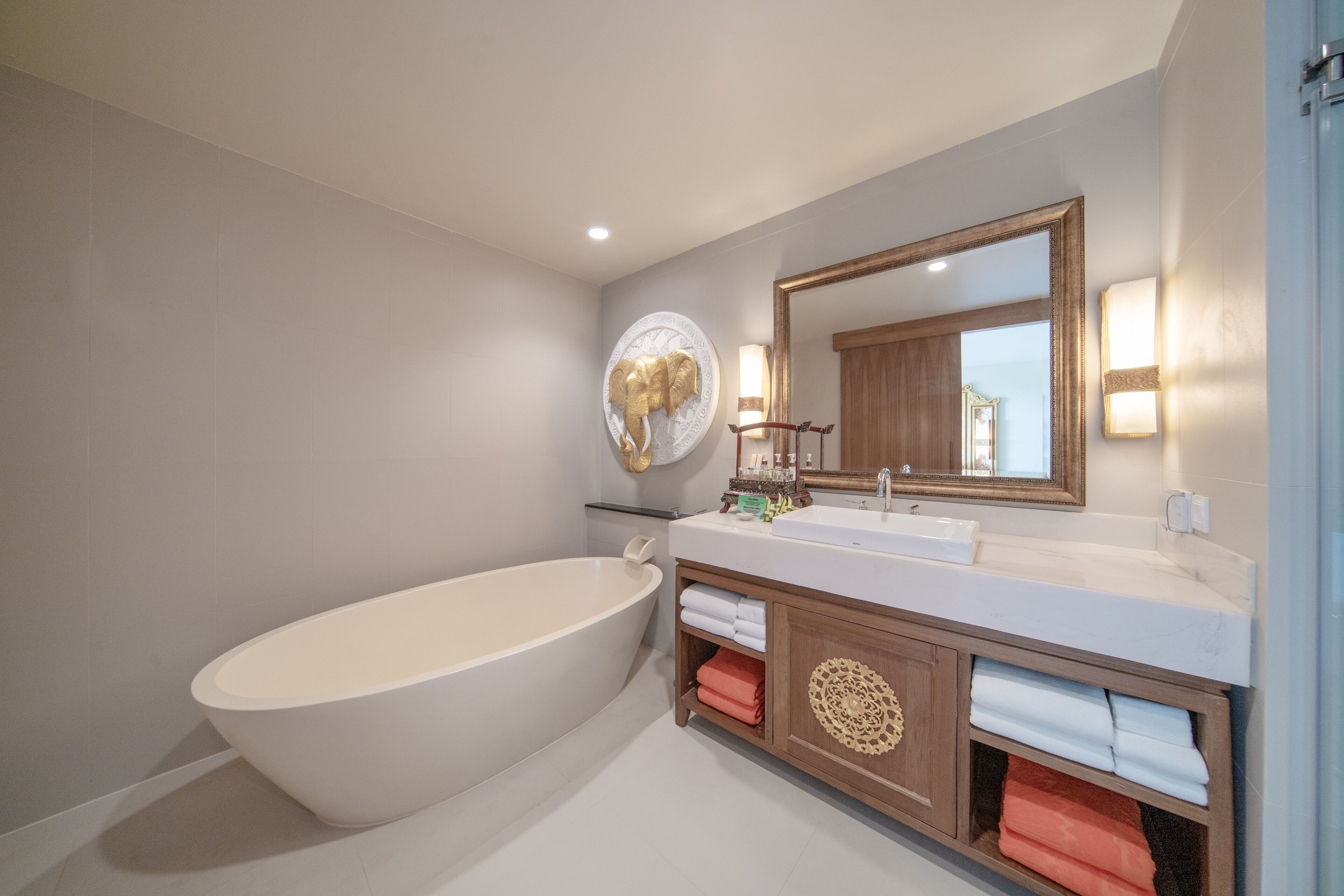 A modern bathroom with a freestanding bathtub, a large mirror, and a vanity with a sink and towel storage.