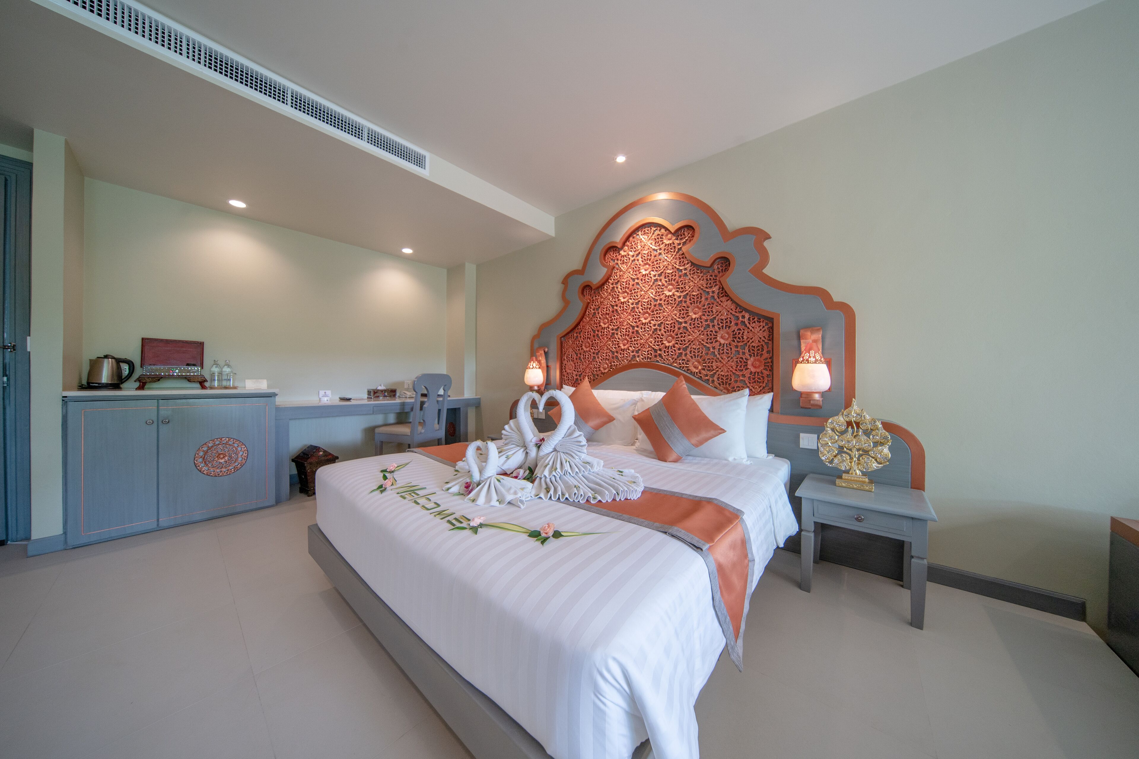 A hotel room with a large bed, a desk, and a wardrobe.