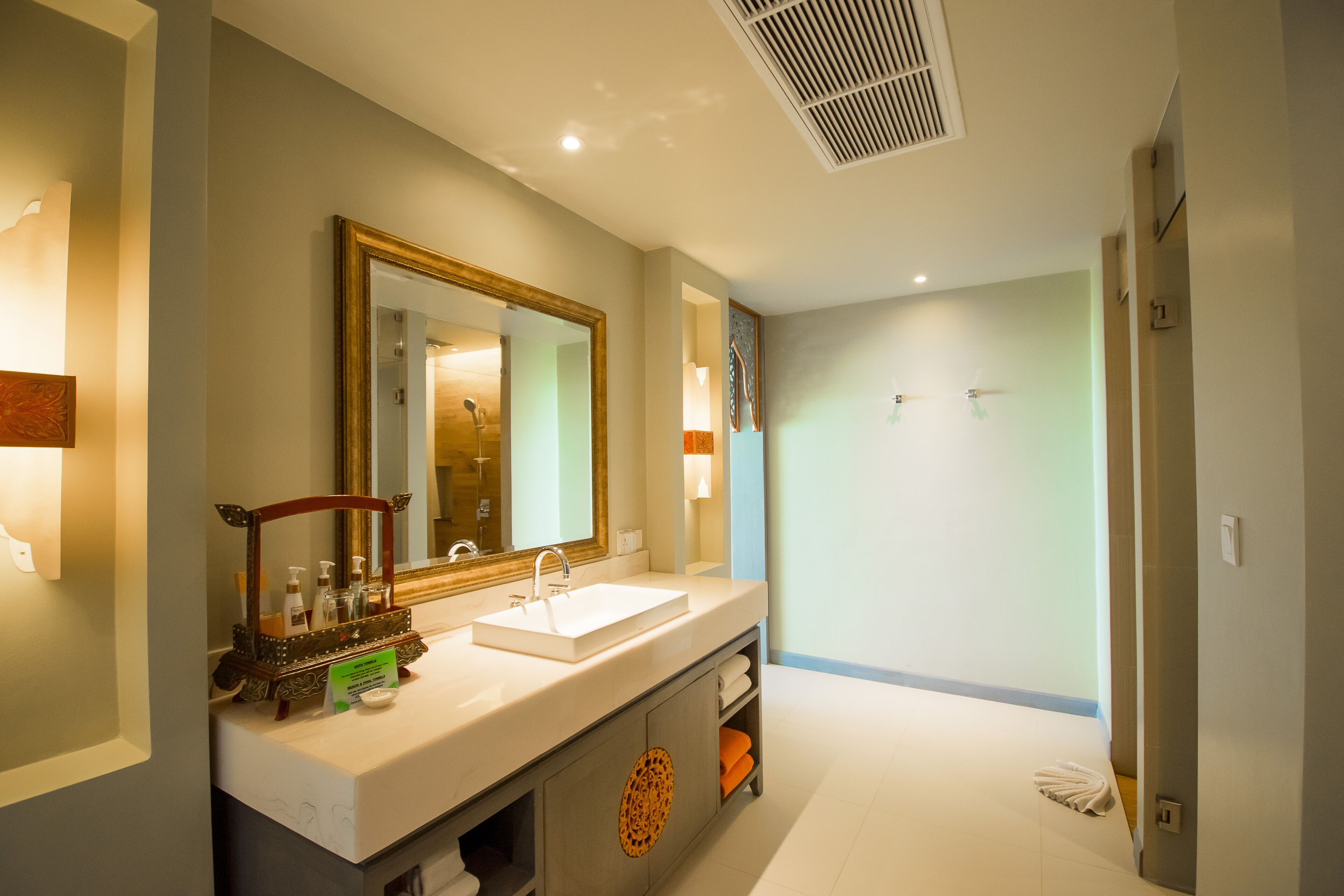 A modern bathroom with a large mirror, two sinks, and a shower area.