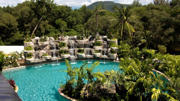 A swimming pool with a waterfall feature surrounded by tropical vegetation. - Maikhao Palm Beach Resort (Mai Khao)