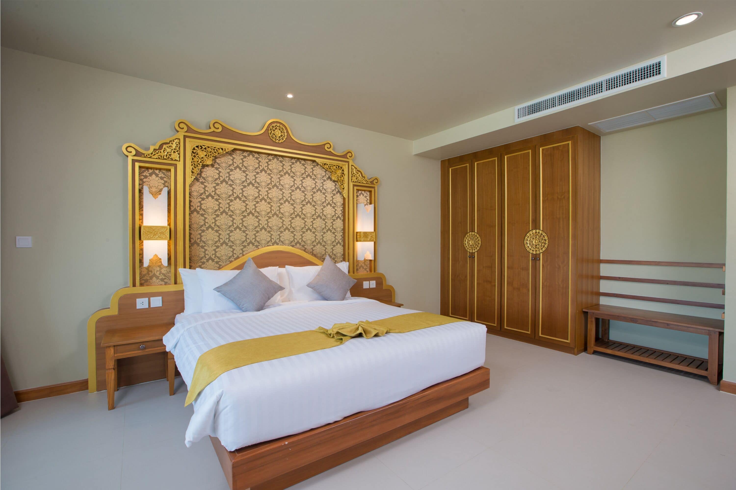 A spacious bedroom with a large bed, wooden wardrobe, and a bench.