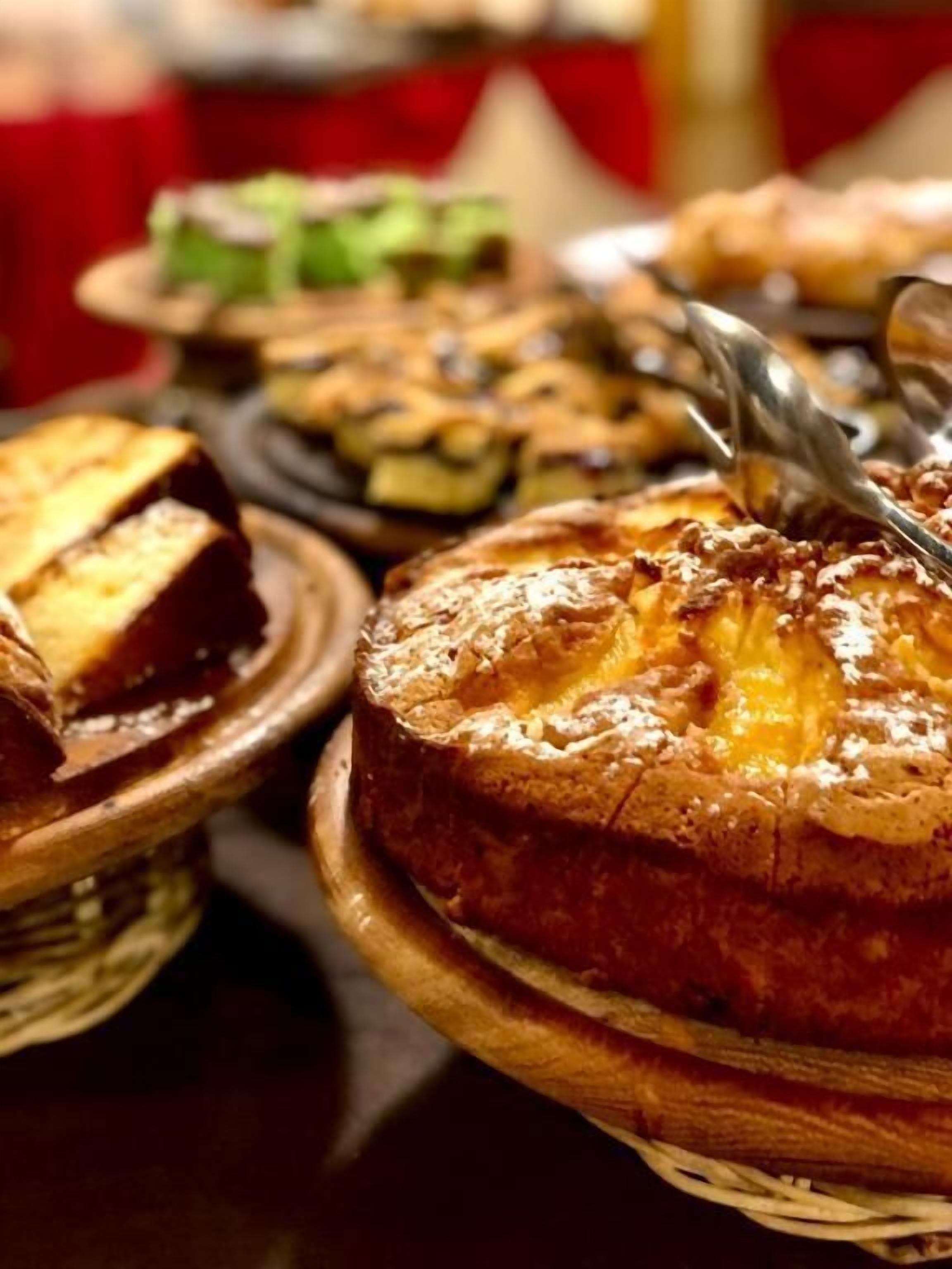 A variety of baked goods on a table, including a pie with a golden-brown crust and a piece of bread.