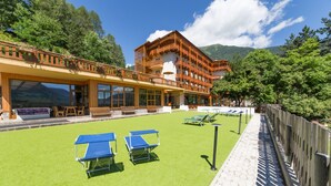A hotel with a pool area, outdoor seating, and a wooden fence. - Hotel Sancamillo (Dimaro Folgarida)