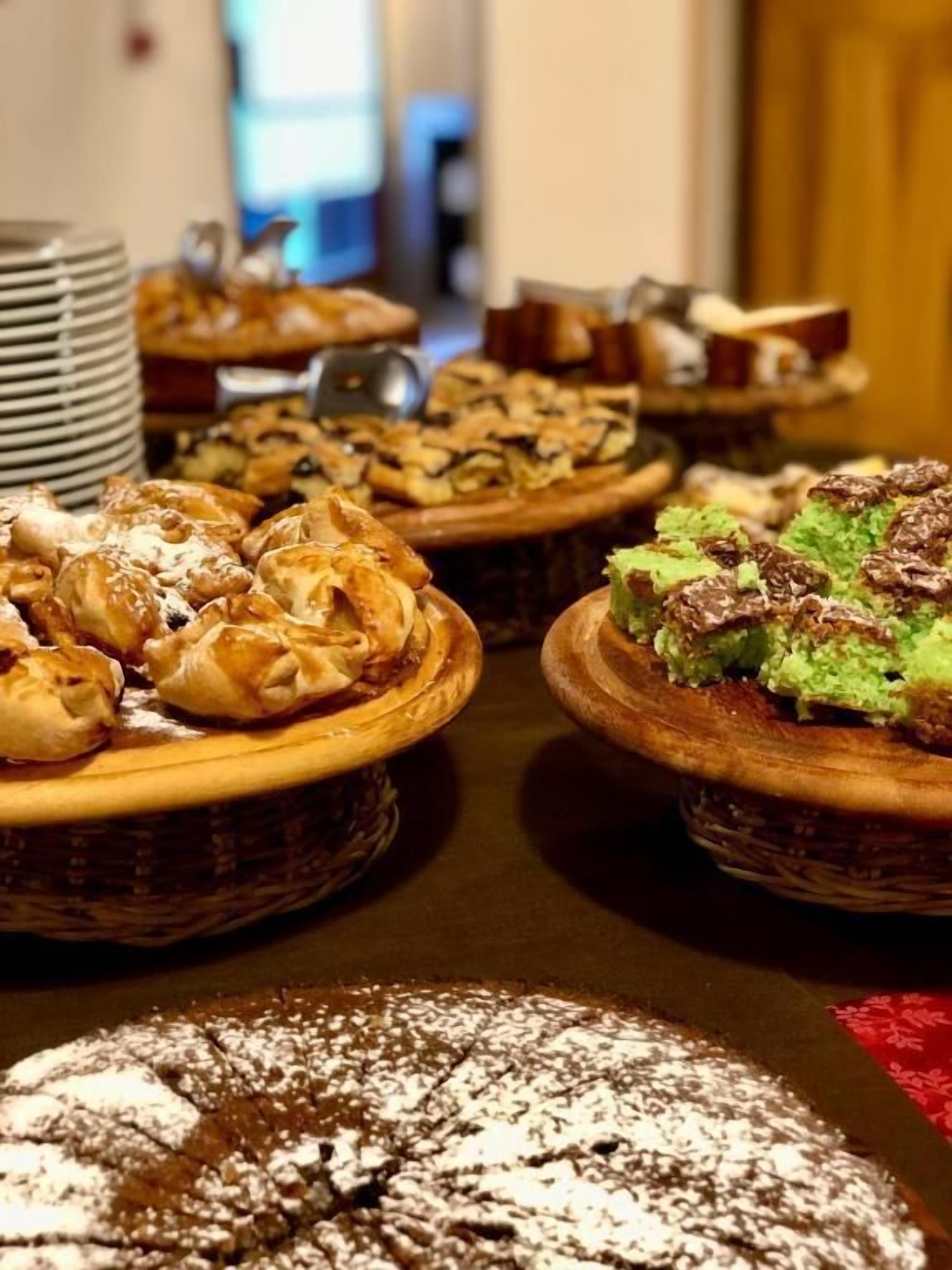 Una mesa de bufé con diversos productos de pastelería, incluyendo pasteles y tartas.