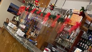 A bar area with a marble counter, various bottles, and a decorative plant. - Hotel Sancamillo (Dimaro Folgarida)