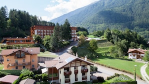 A mountain resort with multiple buildings, including a hotel with balconies and a view of the surrounding forest and hills. - Hotel Sancamillo (Dimaro Folgarida)