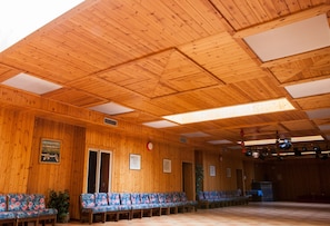 A wooden interior with a high ceiling, benches, and a stage area. - Hotel Sancamillo (Dimaro Folgarida)