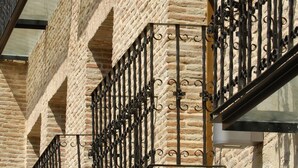 A building with a brick facade and multiple balconies with wrought iron railings. - Hotel Cienbalcones (Daroca)