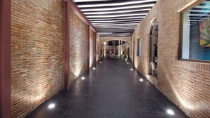 A corridor with brick walls, a dark floor, and a ceiling with black and white beams. - Hotel Cienbalcones (Daroca)
