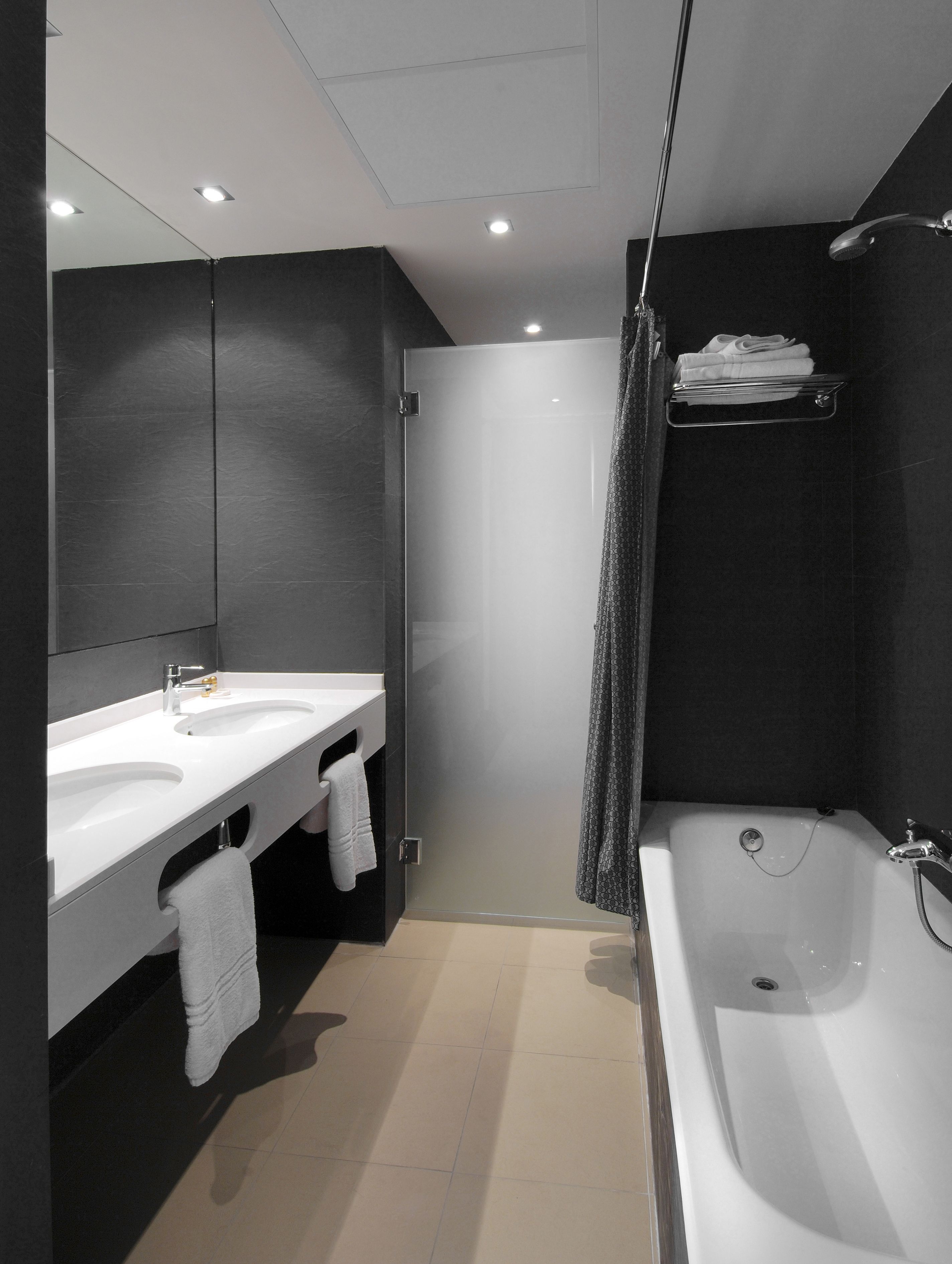 A modern bathroom with a large bathtub, a double sink vanity, and a glass shower enclosure.