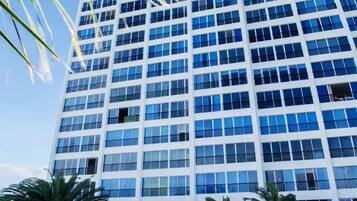 A high-rise building with a pool in front.