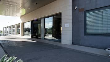 Un bâtiment moderne doté de grandes portes et fenêtres en verre, d’une façade recouverte de carreaux et d’un panneau indiquant qu’il est interdit de se garer.
