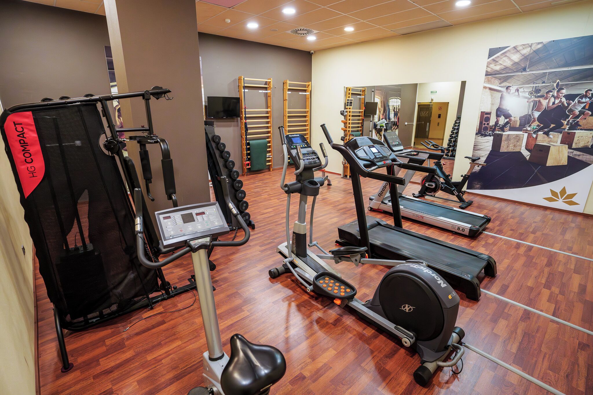 A gym with various exercise equipment including treadmills, an elliptical, and a weight machine.