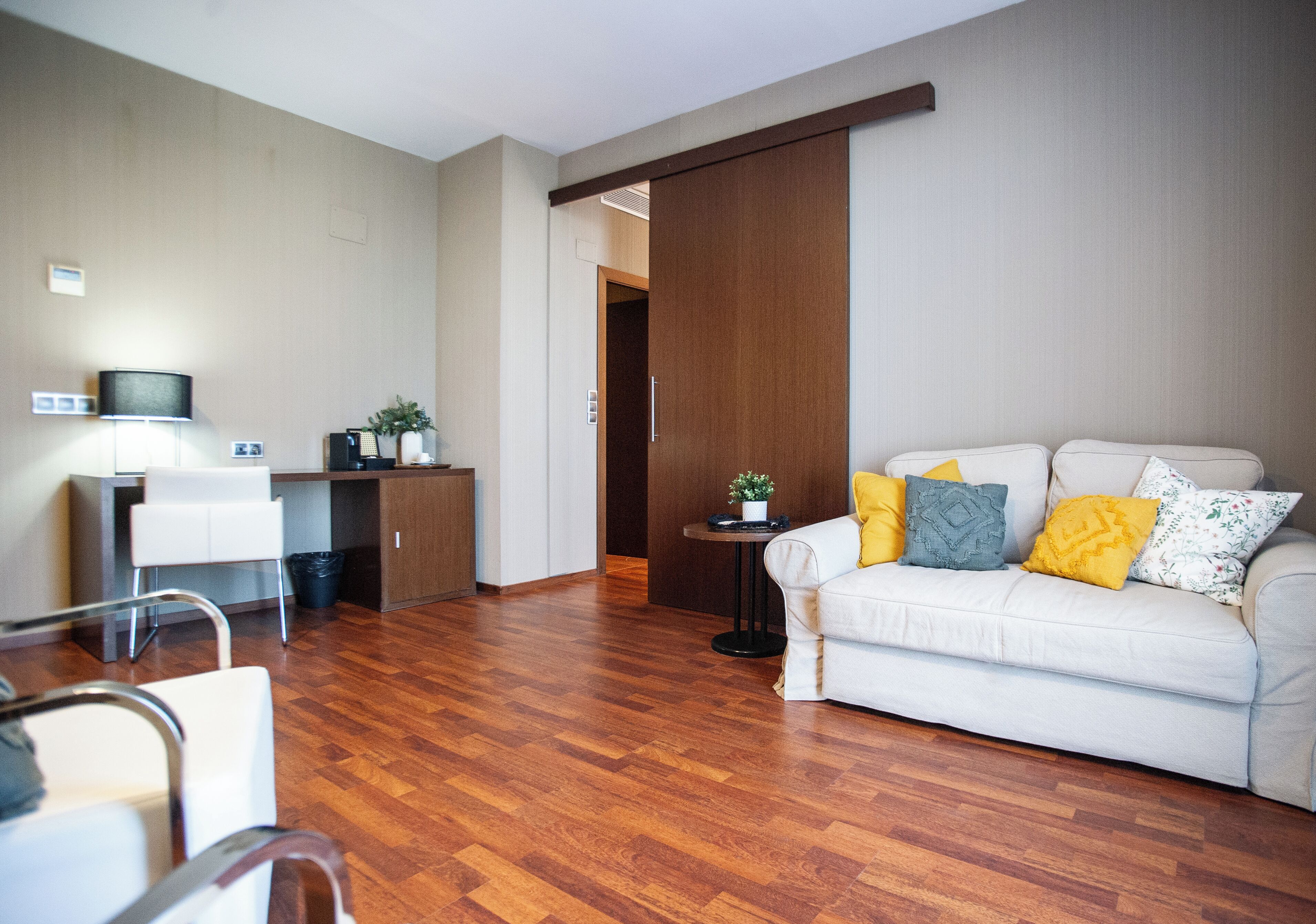A modern living room with a sofa, a coffee table, a TV, and a desk.