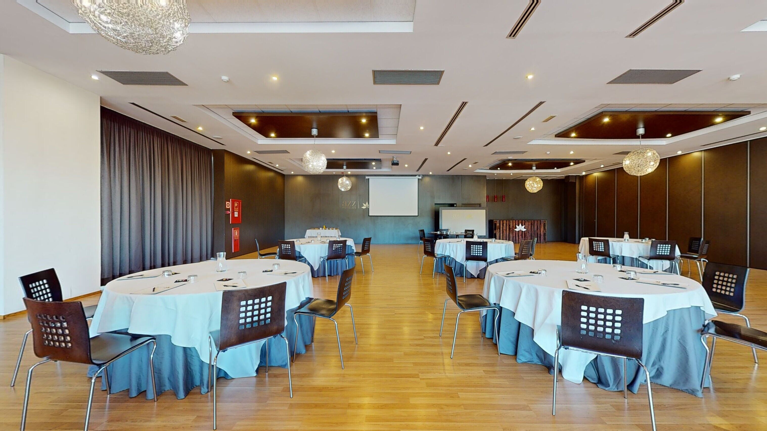A conference room with round tables, chairs, and a projector screen.