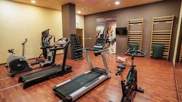 A gym with treadmills, stationary bikes, and dumbbells.