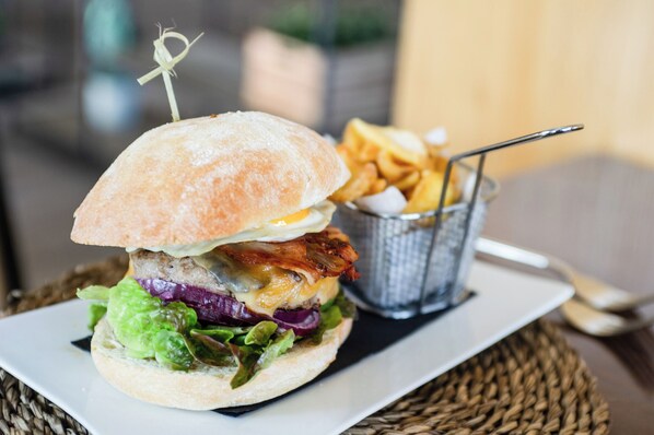 A sandwich with a toothpick, a side of fries, and a fork on a plate. - AZZ Valencia Congress Hotel & Spa (Paterna)