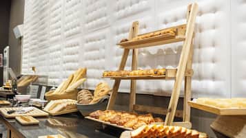 Un bufé con diversas opciones de panadería expuestas en pedestales y bandejas de madera.