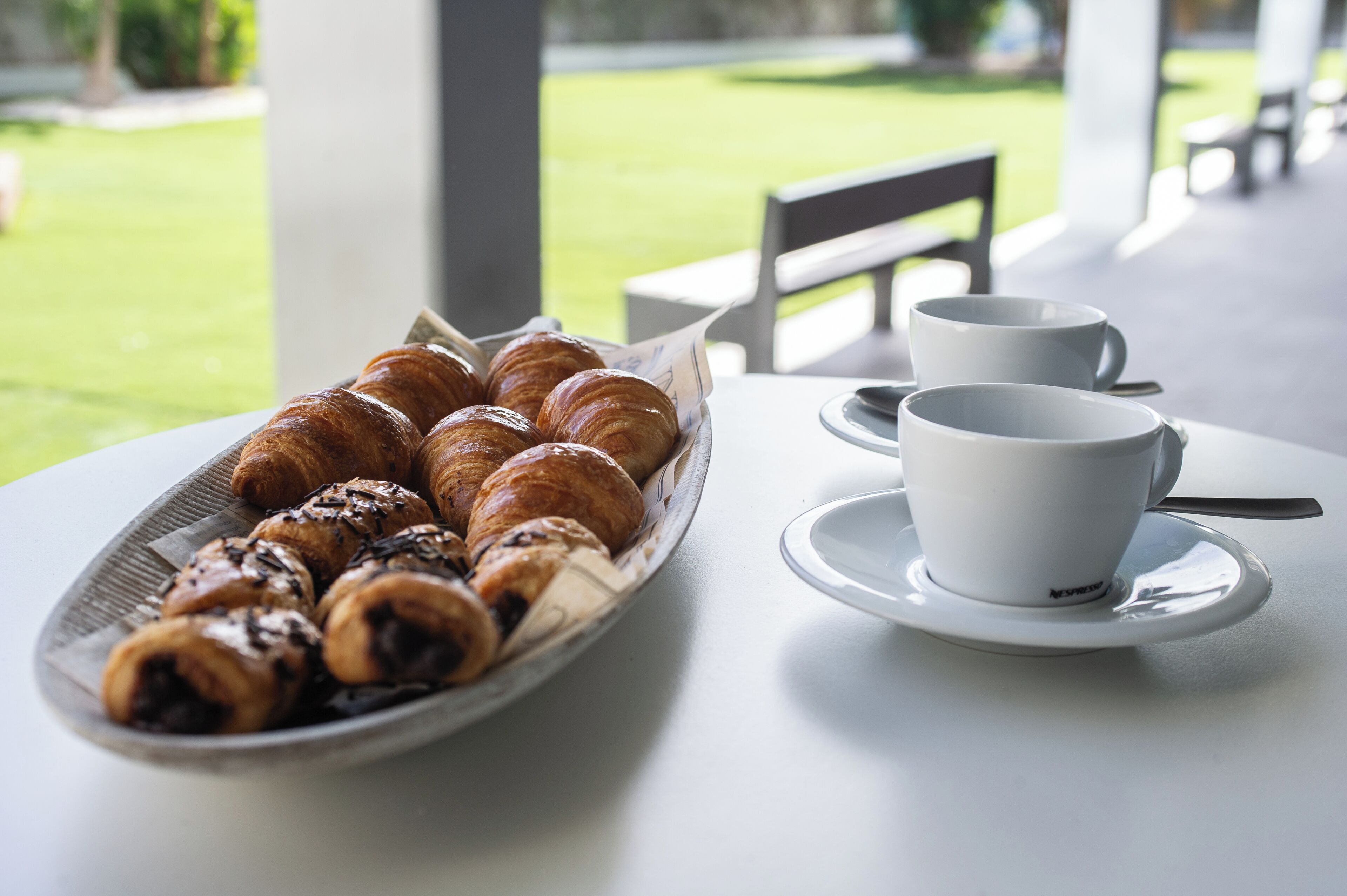 A table with a plate of croissants and a cup of coffee.