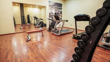 Un gimnasio con equipo de ejercicio, cinta de correr y pesas.