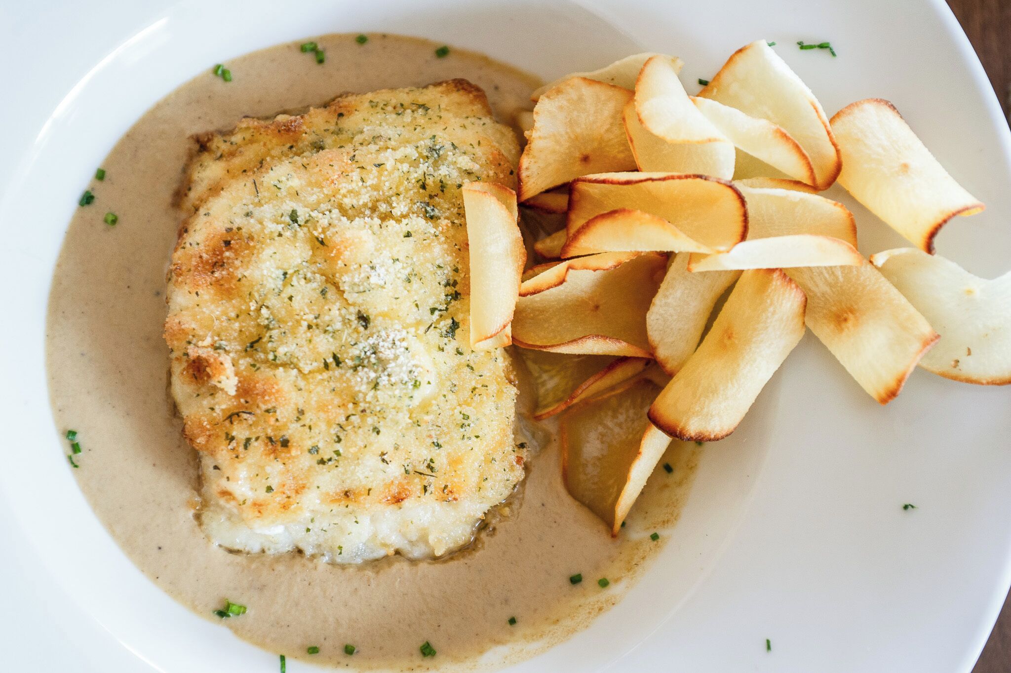 Un plato con un filete de pescado rebozado y rodajas de manzana.