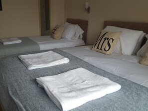 A hotel room with two beds, each with a pillow labeled "Mrs." and "Mr." and neatly folded white towels on the beds. - Kathleen House (Enfield)