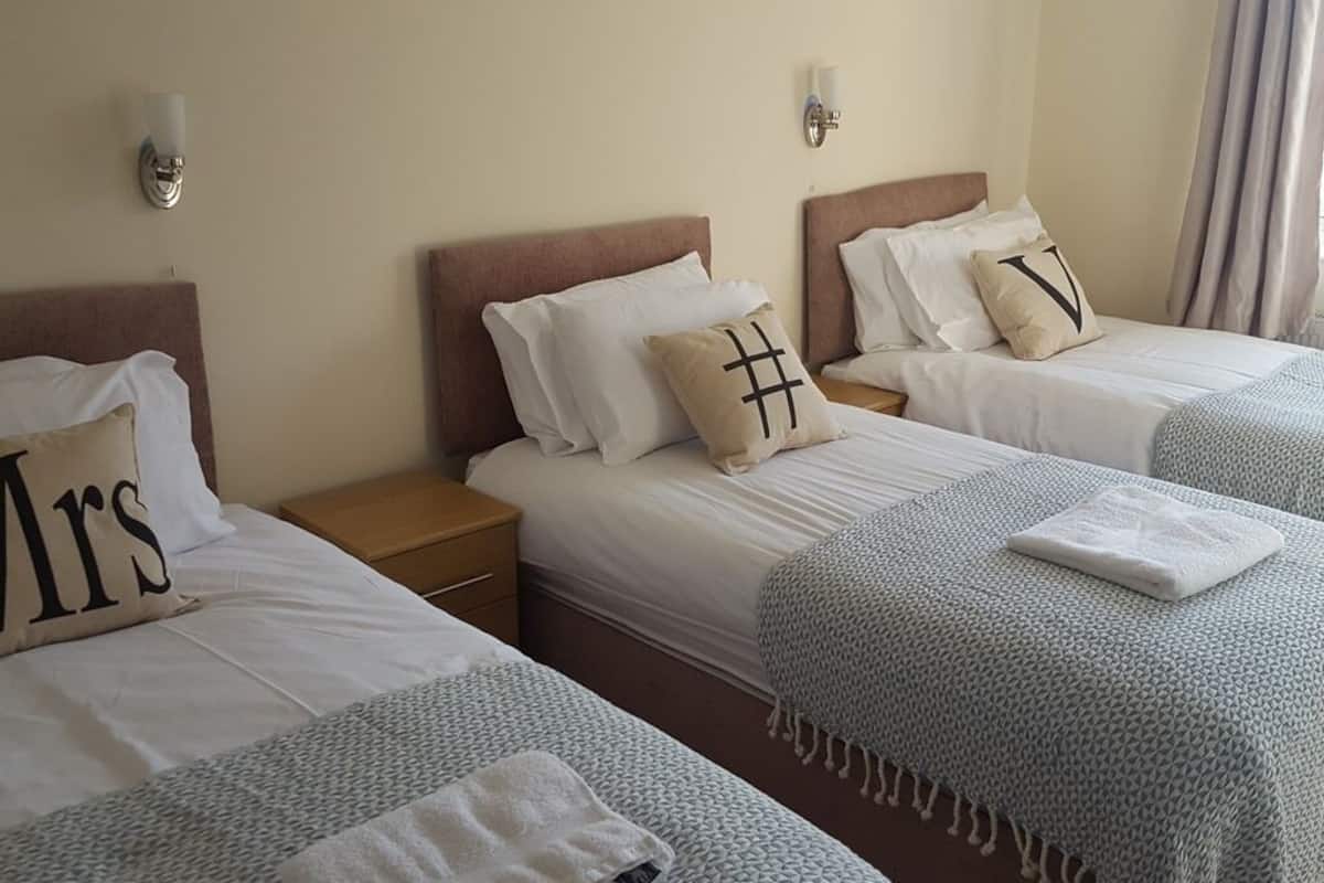 Ein Hotelzimmer mit zwei Betten, jeweils mit Kopfteil, Nachttischen und Wandlampen.