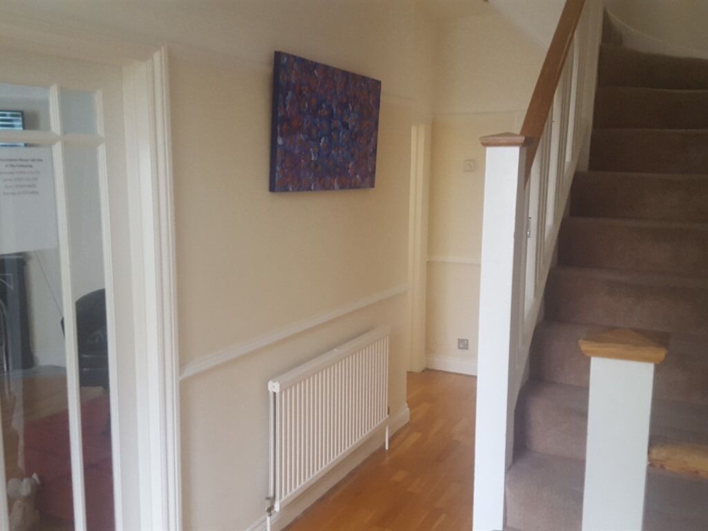 A staircase with wooden steps and a white handrail, leading to an upper floor.
