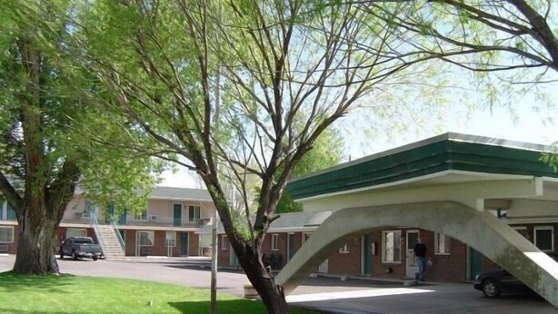 A building with a green roof, a covered outdoor area, and a parking lot.