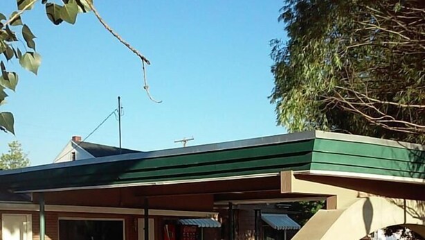 A gas station with a green roof, a concrete floor, and a visible fuel pump. - Gunnison Inn (Gunnison)