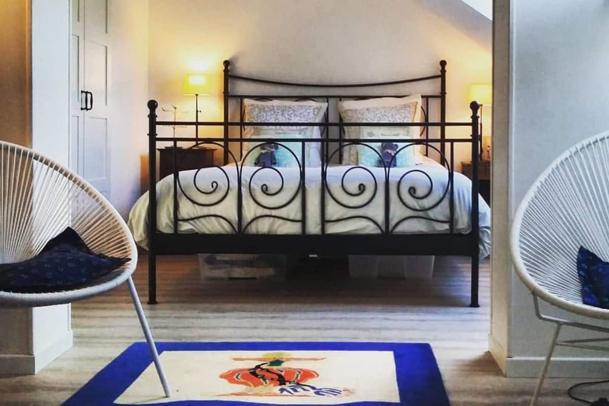 Ein Schlafzimmer mit Himmelbett, zwei Nachttischlampen, einer Hängeleuchte und einem blauen Teppich mit Löwenmuster.