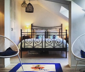 Een slaapkamer met een hemelbed, twee bedlampen, een hanglamp en een blauw vloerkleed met een leeuw dessin.