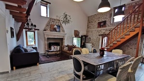 A cozy living room with a fireplace, a dining table, and a staircase.