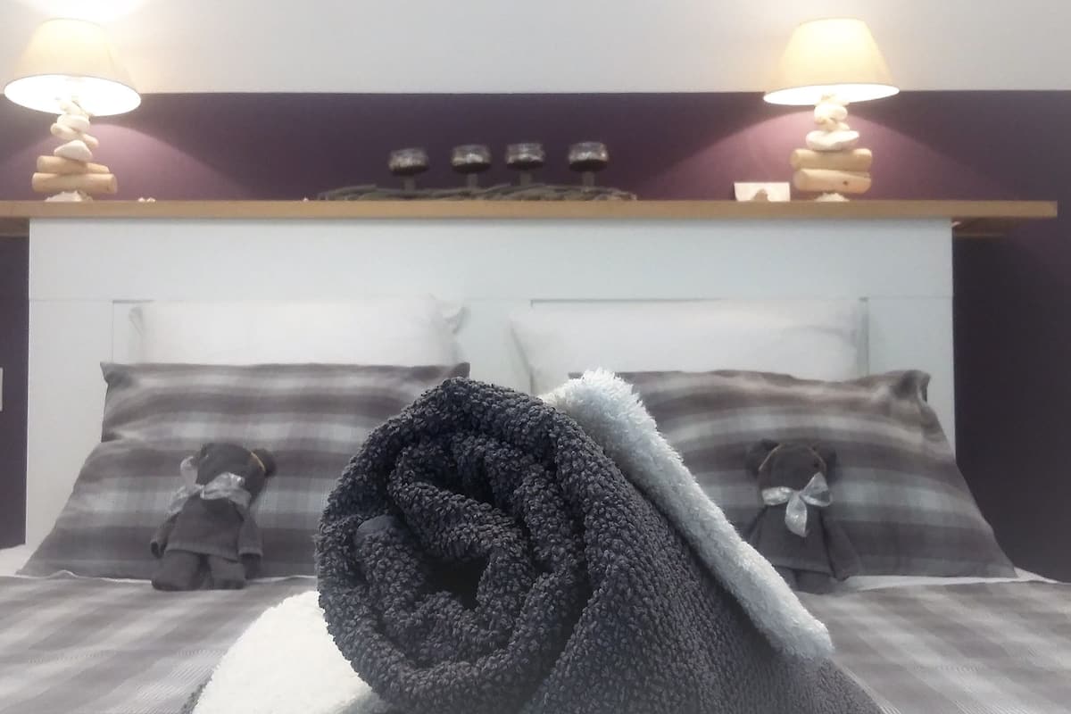 Ein Bett mit zwei Kissen, einer Decke und einem Kopfteil mit Ablagefläche darüber.