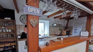 A kitchen with a wooden counter, a clock, and a sign that says "OPEN to the world".