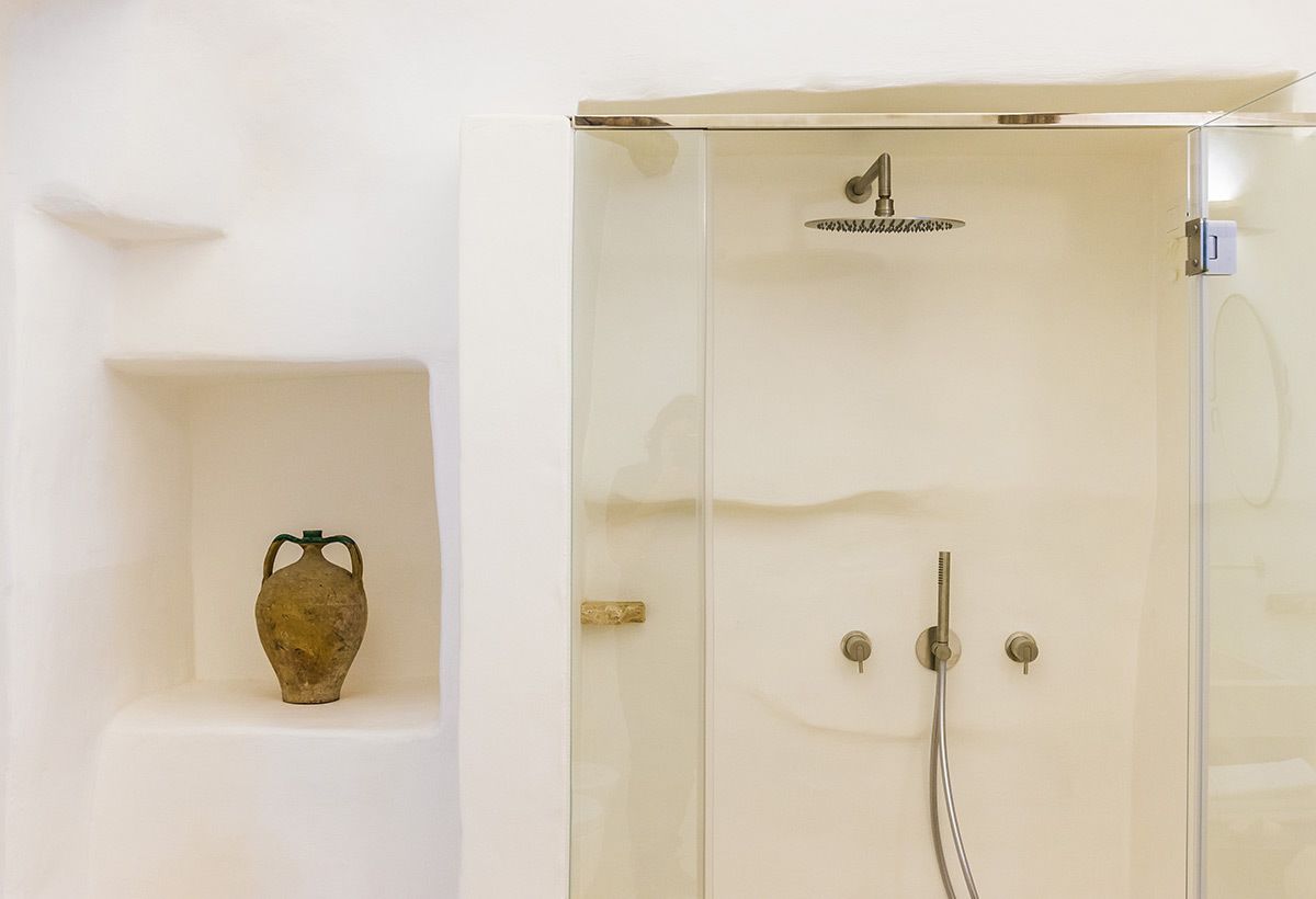 Een moderne badkamer met een douchecabine van glas, een klein plankje met een decoratieve vaas, en een minimalistisch ontwerp.