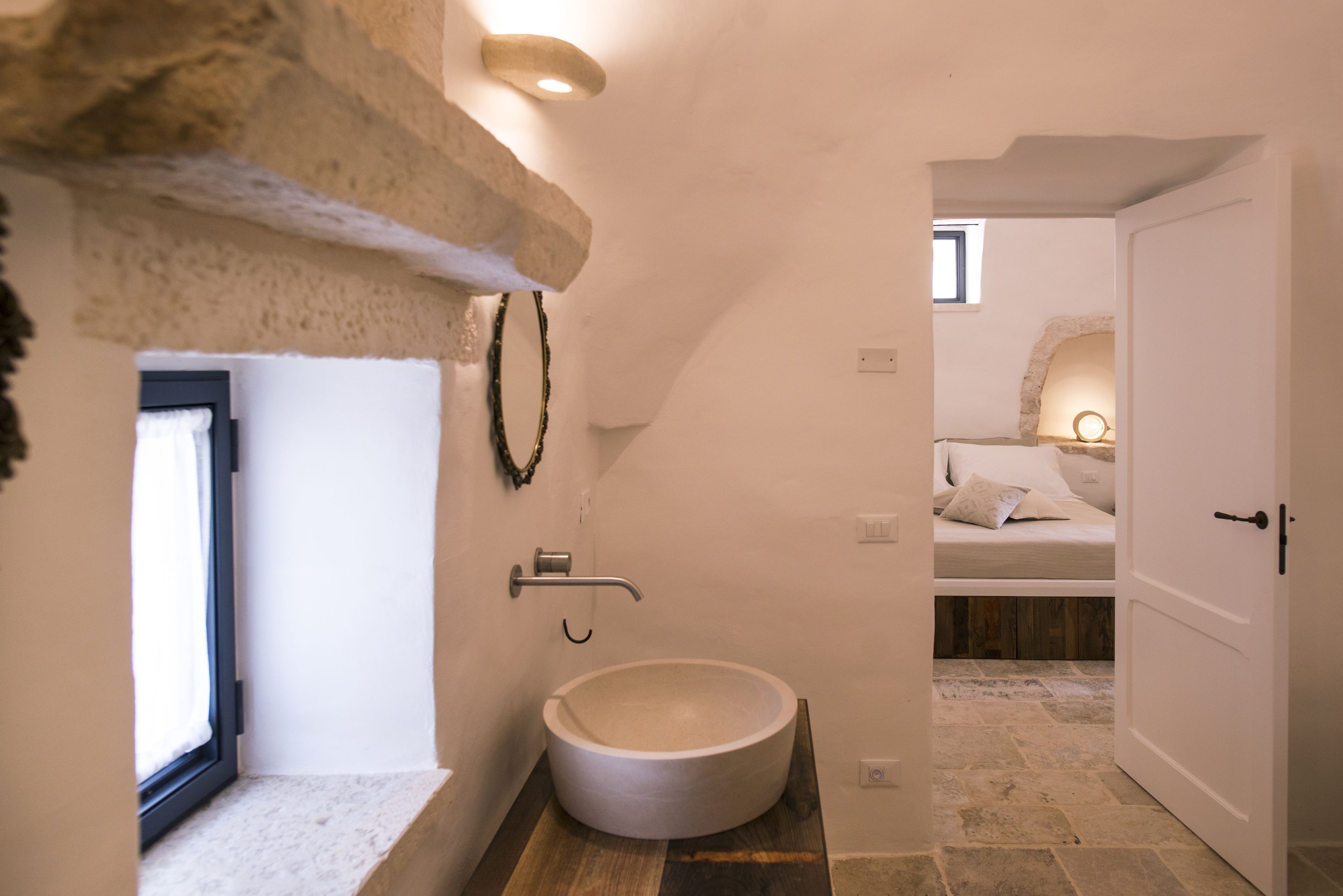Un baño moderno con un lavabo redondo, un perchero y una zona de ducha.