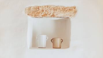 Una estantería blanca con dos tazas de cerámica, una blanca y otra marrón.