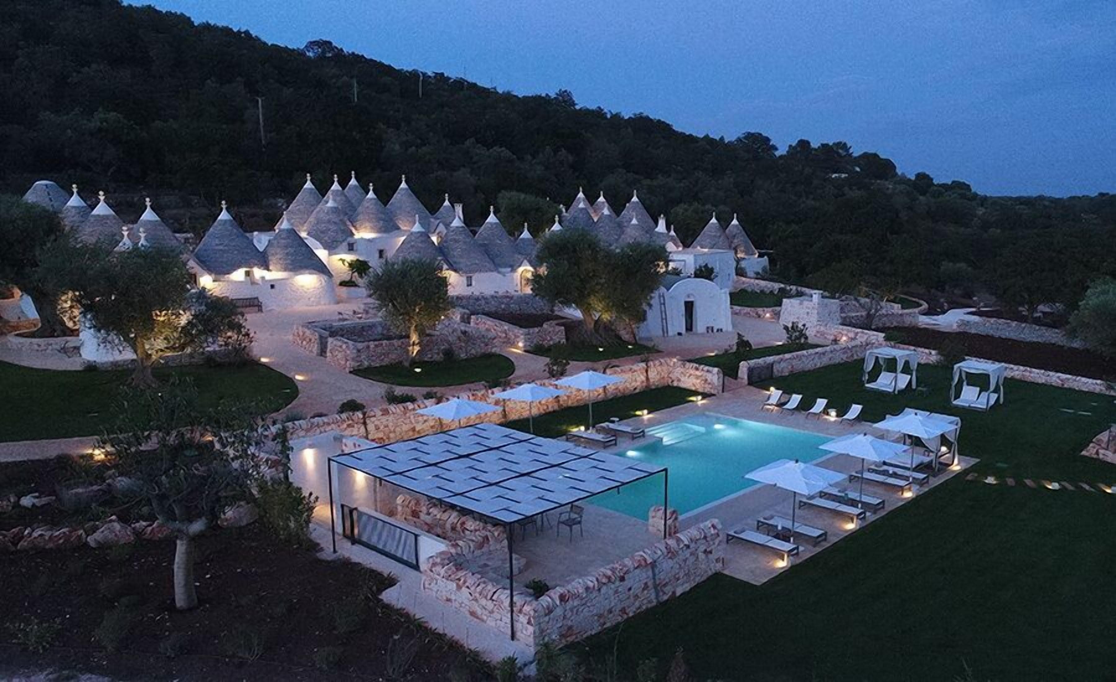 Ein Resort mit mehreren gebäudeartigen Bauten mit Kegeldächern, einem Schwimmbad und Außenbereich-Sitzgelegenheiten.