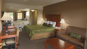 A hotel room with a bed, a sofa, a desk, and a chair. - Travelers Inn (Elizabethton)