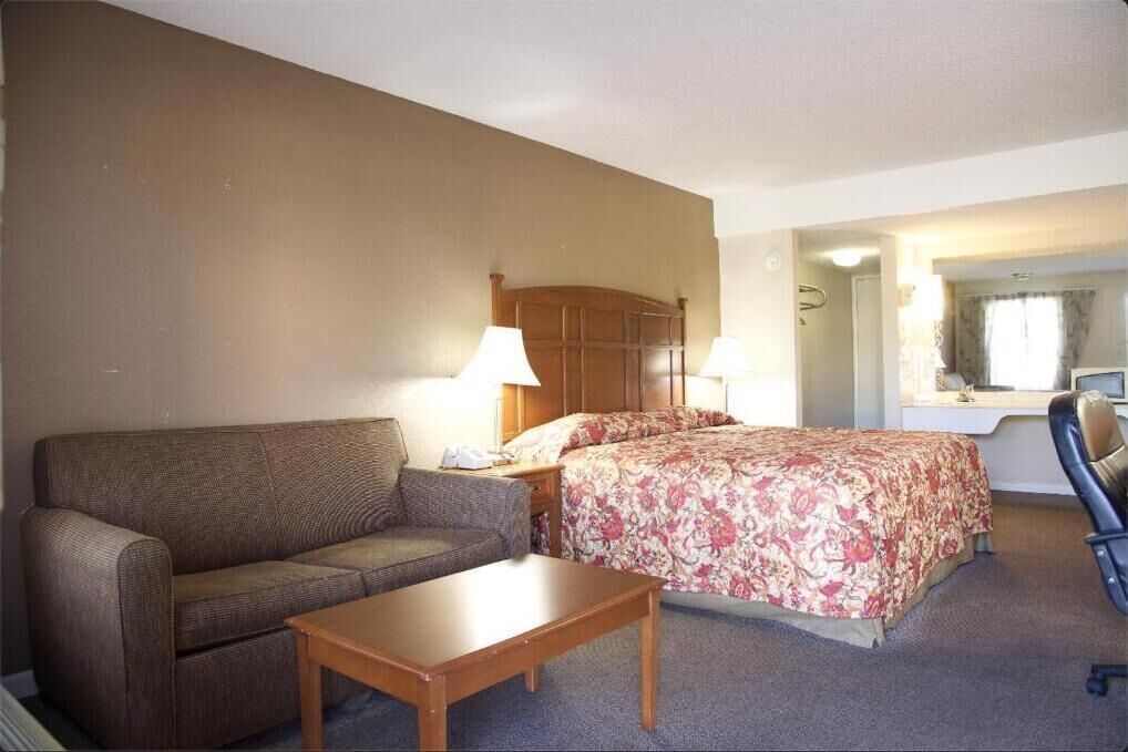 A hotel room with a bed, a sofa, a desk, and a chair.