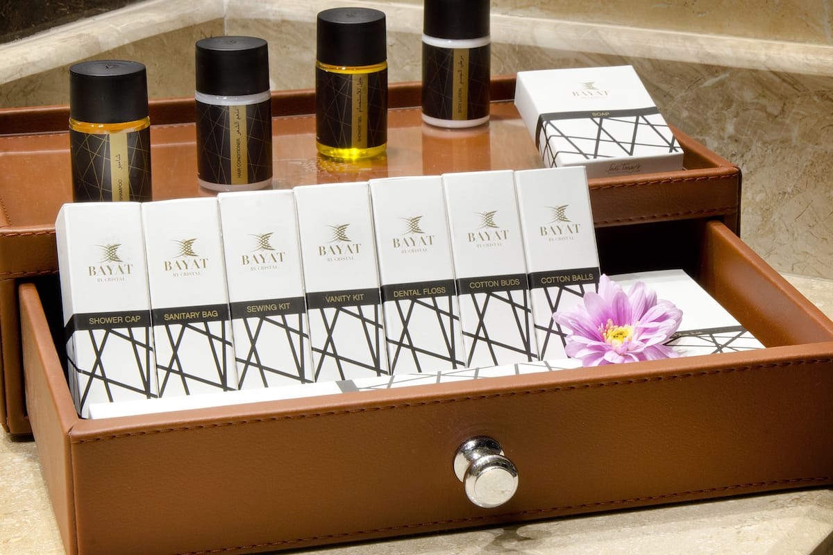 Une trousse de toilette en cuir contenant divers articles, notamment un bonnet de douche, un sac à articles d'hygiène féminine, une trousse de couture, une trousse de maquillage, du fil dentaire et des cotons-tiges.