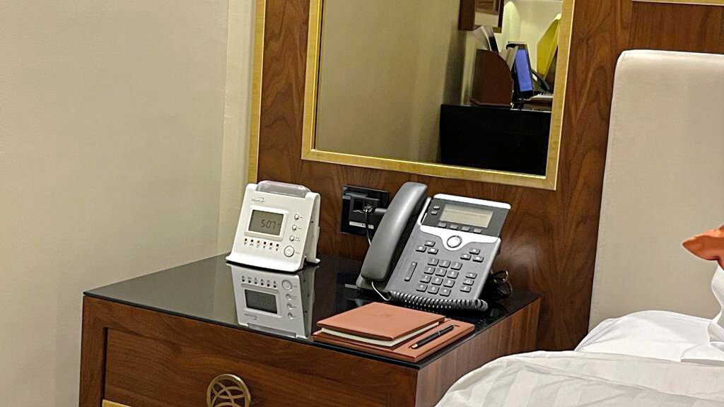 Une chambre d’hôtel avec un bureau en bois, un téléphone, un bloc-notes et un miroir.