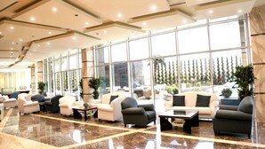 A spacious lobby with multiple seating areas, large windows, and a polished marble floor.