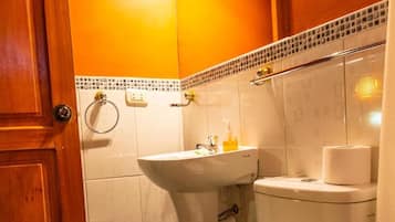 Un baño con inodoro, lavamanos y puerta de madera.
