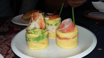 Une assiette comprenant trois amuse-gueule : de l’avocat, des crevettes et une salade crémeuse.