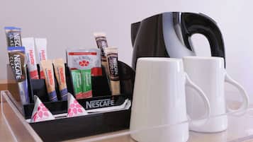 Un coin café avec des produits Nescafé, deux tasses blanches et une cafetière noire, le tout posé sur une surface claire.